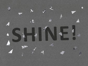 Shine! Das Wort "Shine" auf Sonderpapier mit silbernem Konfetti